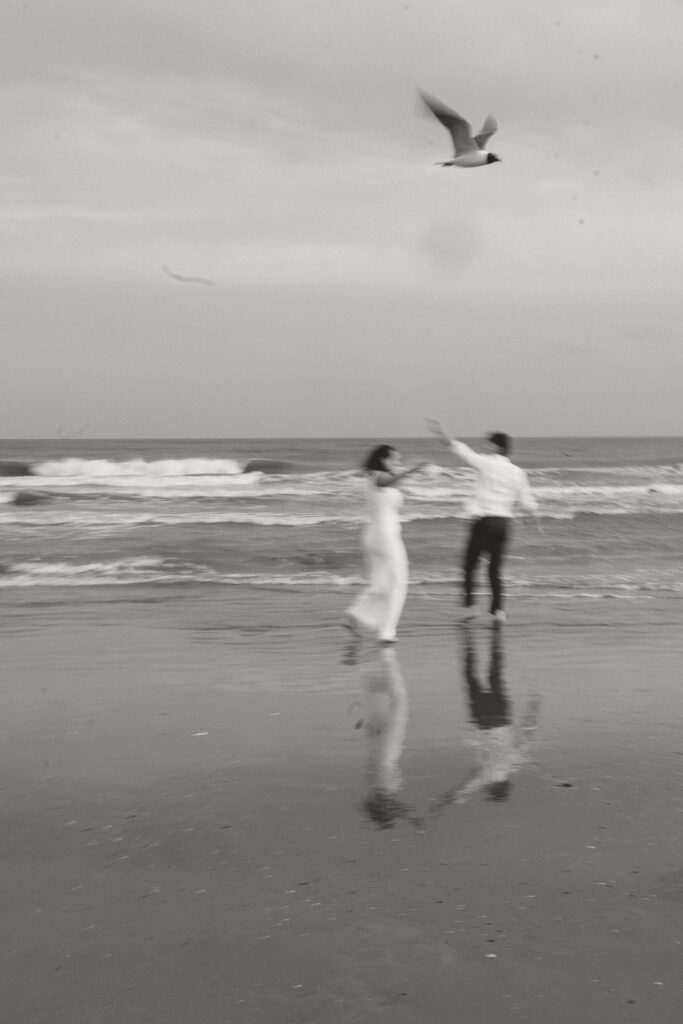 Couple running around with the seagulls at their engagement session at Folly Beach in Charleston SC. 