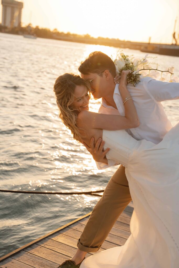 Soft golden hour light over the Charleston waterfront during a modern coastal sailboat elopement.

