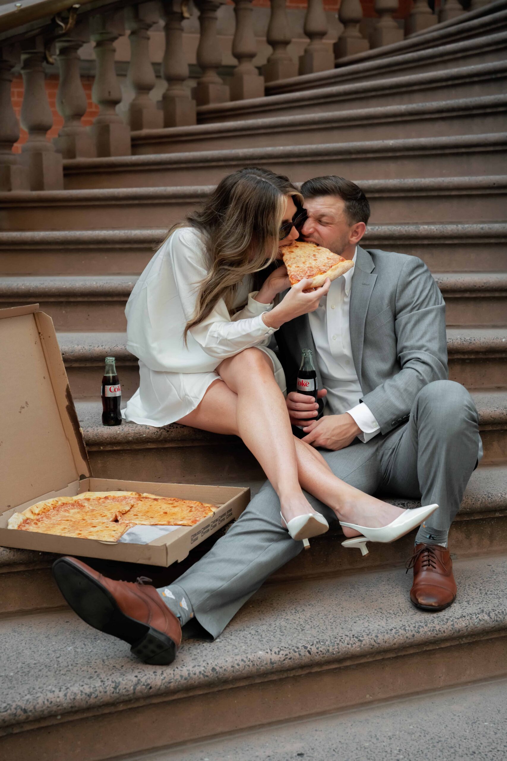 Philly Engagement Session with the couple sitting on the stairs of the union league building eating a pizza together.